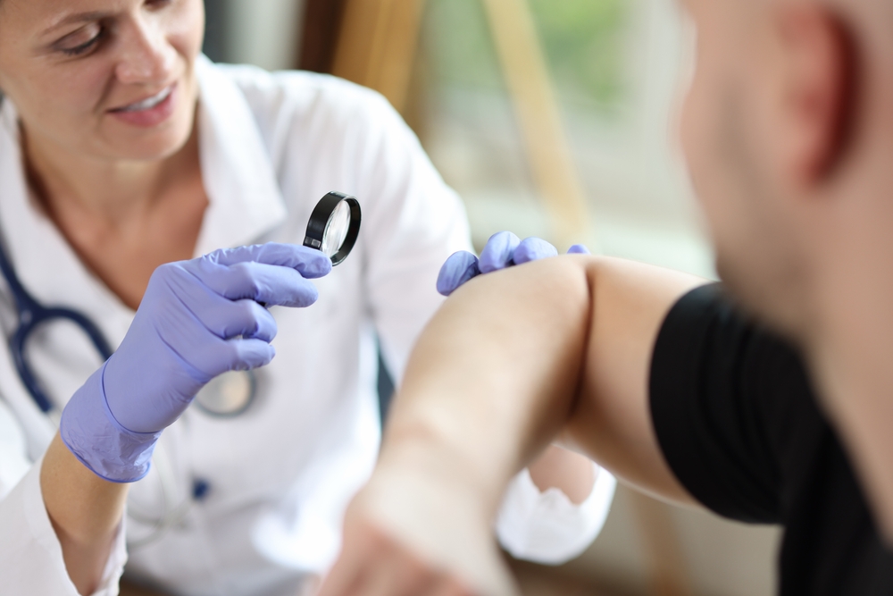 Senior man discussing ongoing pain with a doctor after an injury.